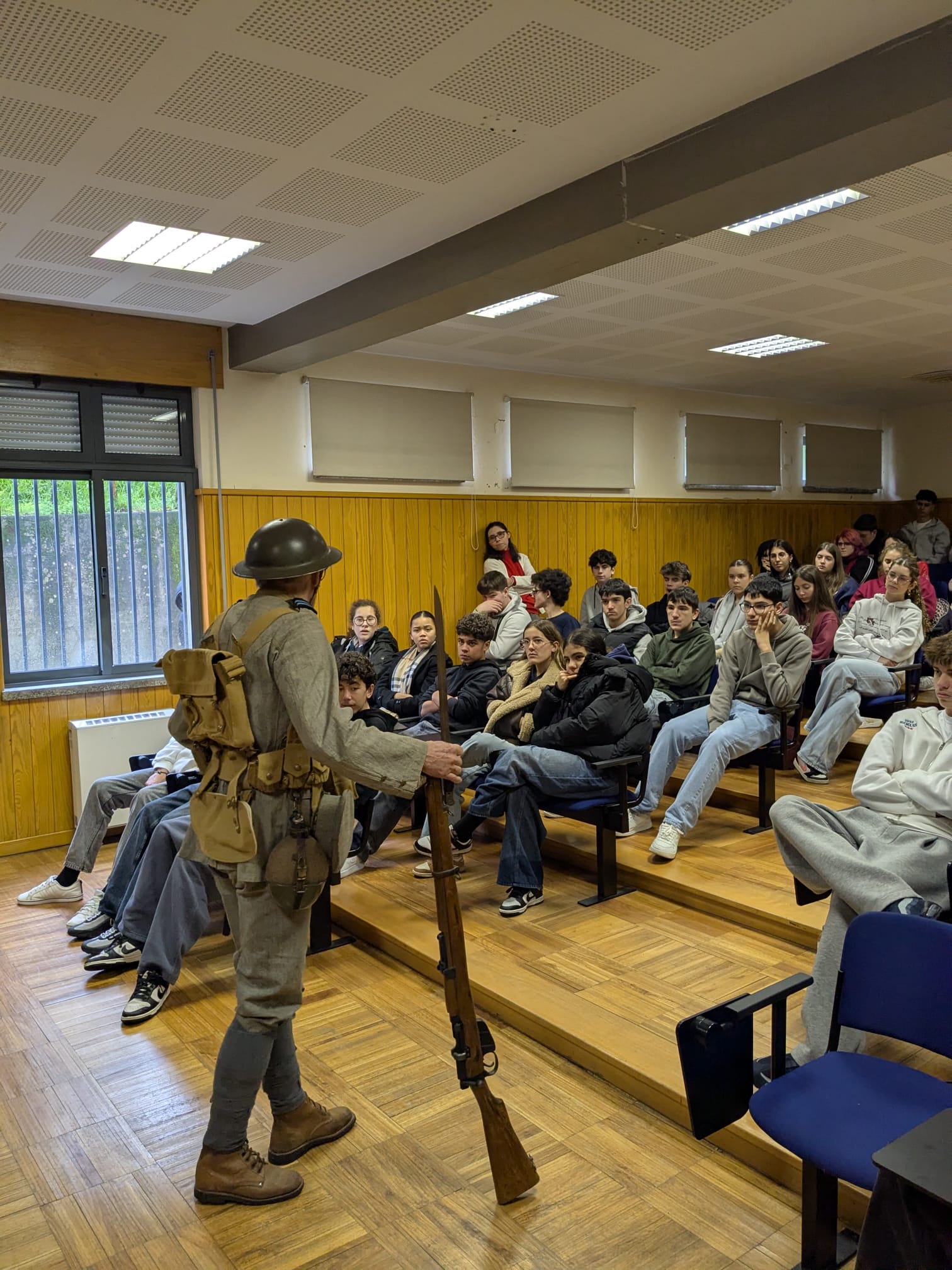 No dia 27 de janeiro de 2026, os alunos do 9.º ano participaram numa atividade que permitiu consolidar as aprendizagens sobre a Primeira Guerra Mundial. Após a visualização do documentário da RTP1 “Portugueses nas Trincheiras”, assistiram a uma dramatização protagonizada pelo neto do Soldado António Pereira dos Santos. Com indumentária completa, arma e baioneta, o “soldado” deu vida ao testemunho real do seu avô, combatente e prisioneiro em La Lys, com base no seu diário de guerra. A apresentação, dinâmica e impactante, despertou grande interesse nos alunos. O diário foi posteriormente publicado no livro “A Saga de um Combatente na I Guerra Mundial – de Chaves a Copenhaga”.